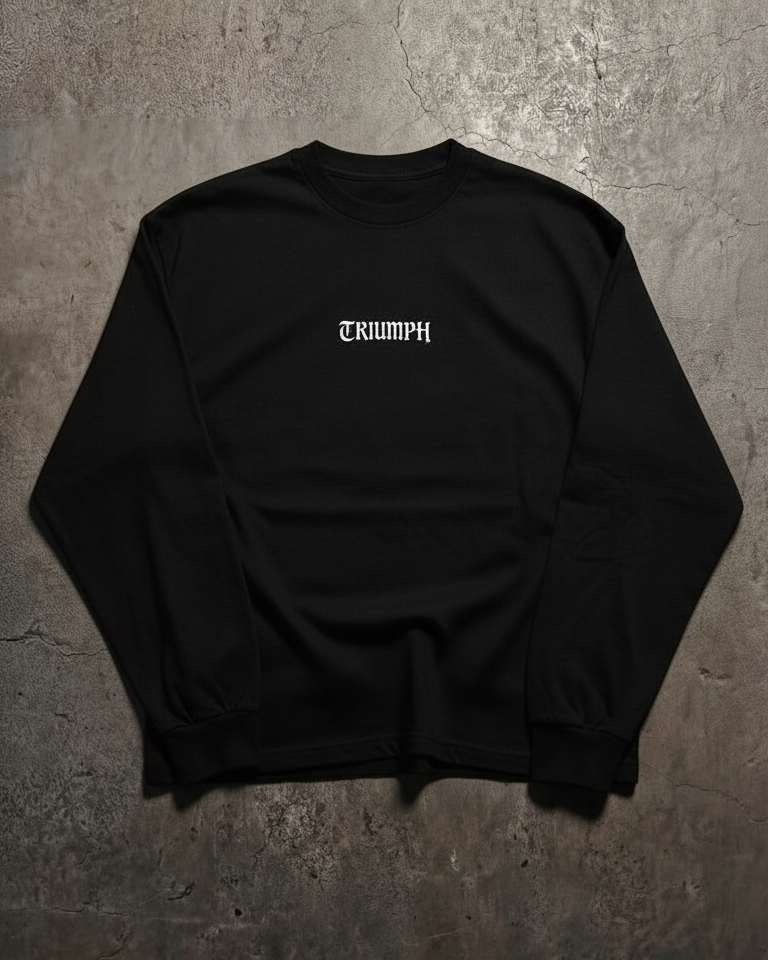 Black long sleeve shirt with 'TRIUMPH' logo on a concrete surface
